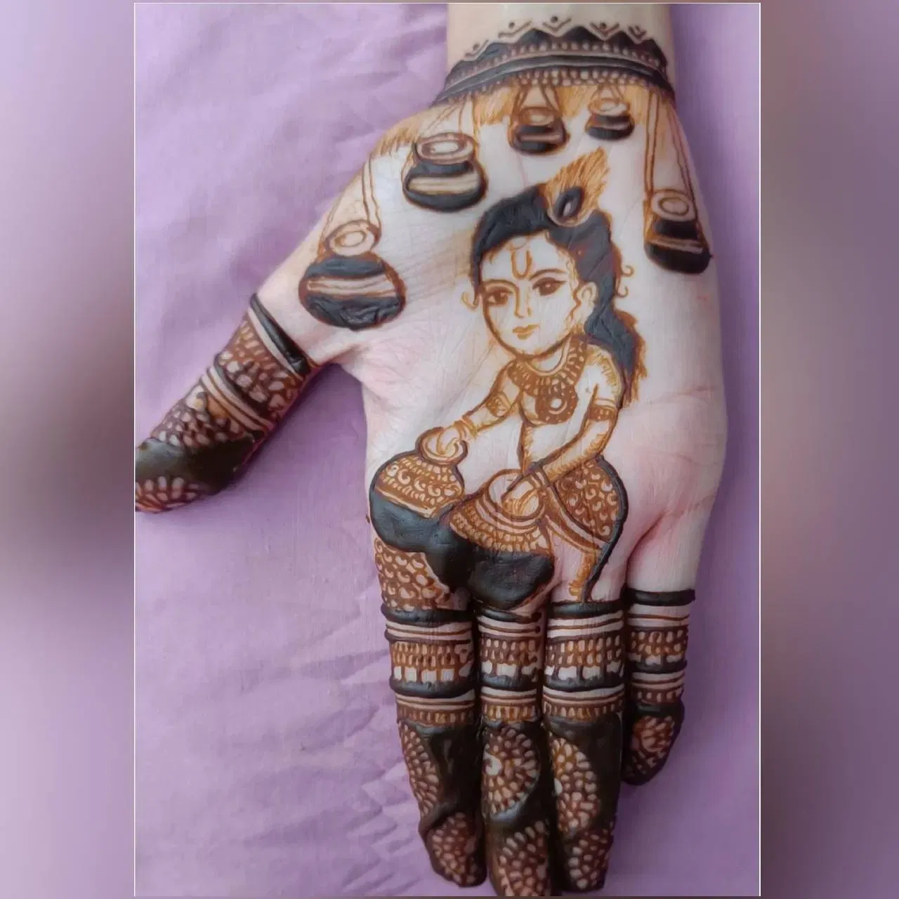 এই মেহেন্দি ডিজাইনত শ্ৰীকৃষ্ণক শিশু কালত হাতত দৈৰ কলহ এটা ধৰি থকা দেখুওৱা হৈছে। তাৰ চাৰিওফালে কলহবোৰ ওলমি আছে। এই ডিজাইনটোও বৰ ধুনীয়া। আপুনি জন্মাষ্টমীত এই ধৰণৰ ডিজাইনৰ মেহেন্দি আকিব পাৰে।