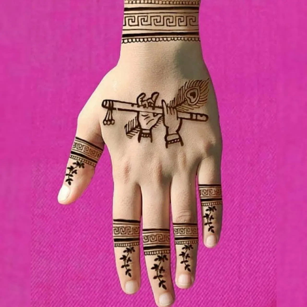 মেহেন্দিৰ এই ডিজাইনটো অতি সৰল আৰু আকিবলৈ সহজ। ইয়াত ভগৱান কৃষ্ণৰ হাতত বাঁহী আৰু ময়ূৰৰ পাখি দেখুওৱা হৈছে। জন্মাষ্টমী উপলক্ষে আপুনি এনেদৰে বাঁহী, ময়ূৰৰ পাখি ষ্টাইলৰ ডিজাইনো আকিব পাৰে।