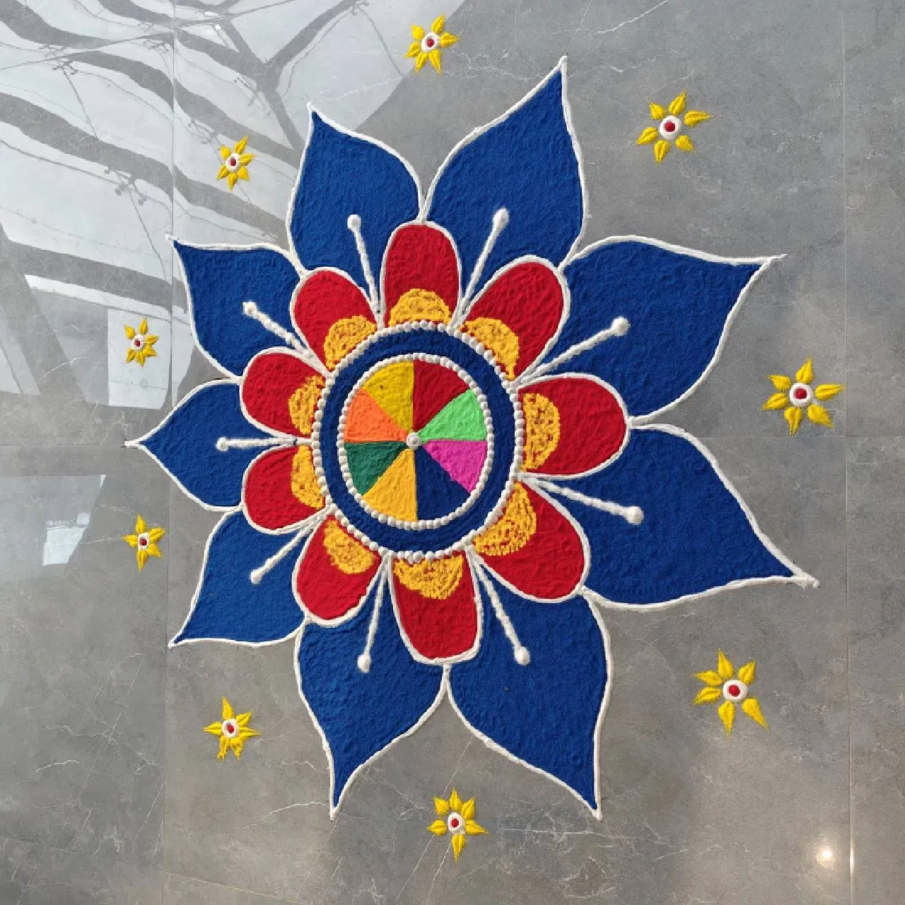 আল্পনাৰ এই ডিজাইনটোও বনাবলৈ অতি সহজ। ঘৰত বা মন্দিৰৰ যিকোনো ঠাইতে এই ডিজাইন বনাব পাৰিব। নীলা, হালধীয়া আৰু মেৰুণ ৰঙৰ এই ডিজাইনটো দেখাত অতি সুন্দৰ। লগতে ওচৰতে সৰু সৰু তৰা তৈয়াৰ কৰা হৈছে।