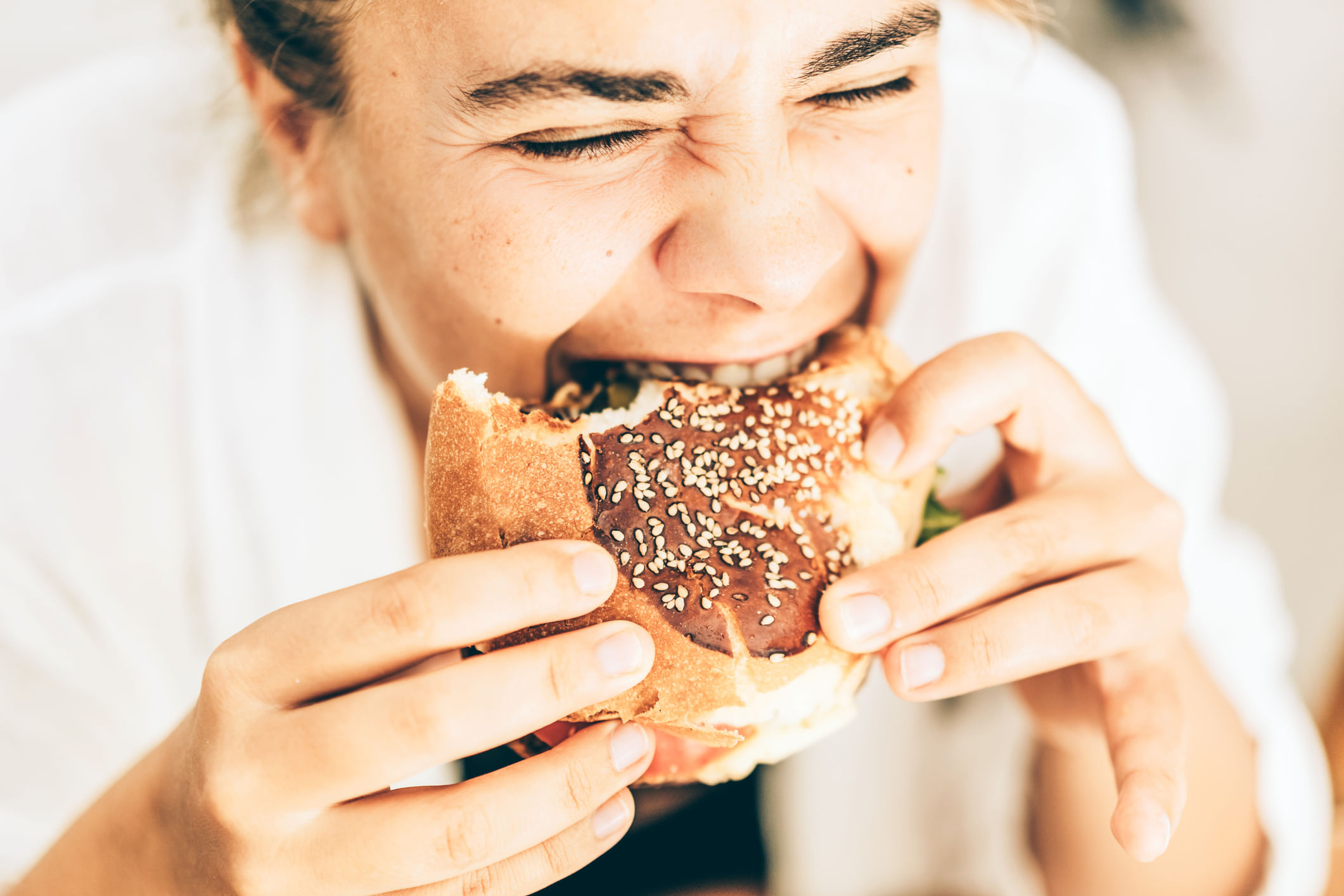 Young Woman Enjoying A Delicious Sesame Burger With Intense Flavor